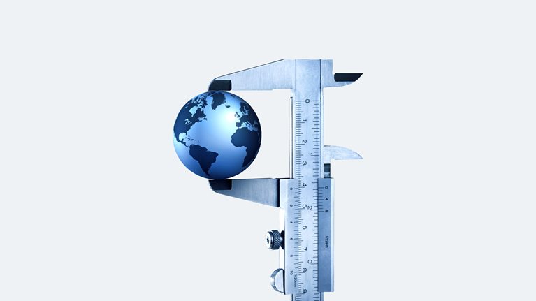 A globe in a vernier caliper set against a light gray background.